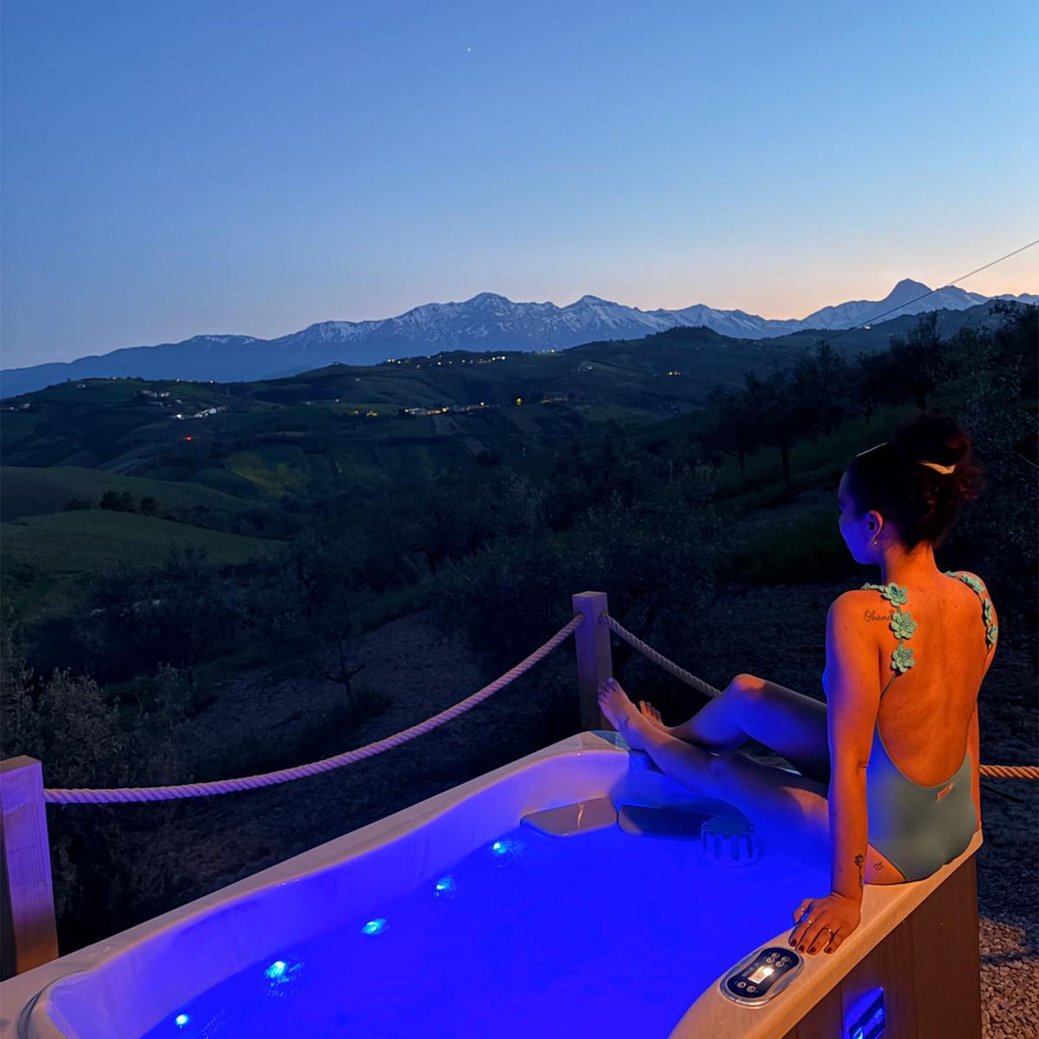 Person relaxing in a hot tub with mountain views at night